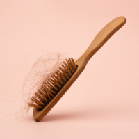 wooden hair brush with lost hair on the pink background